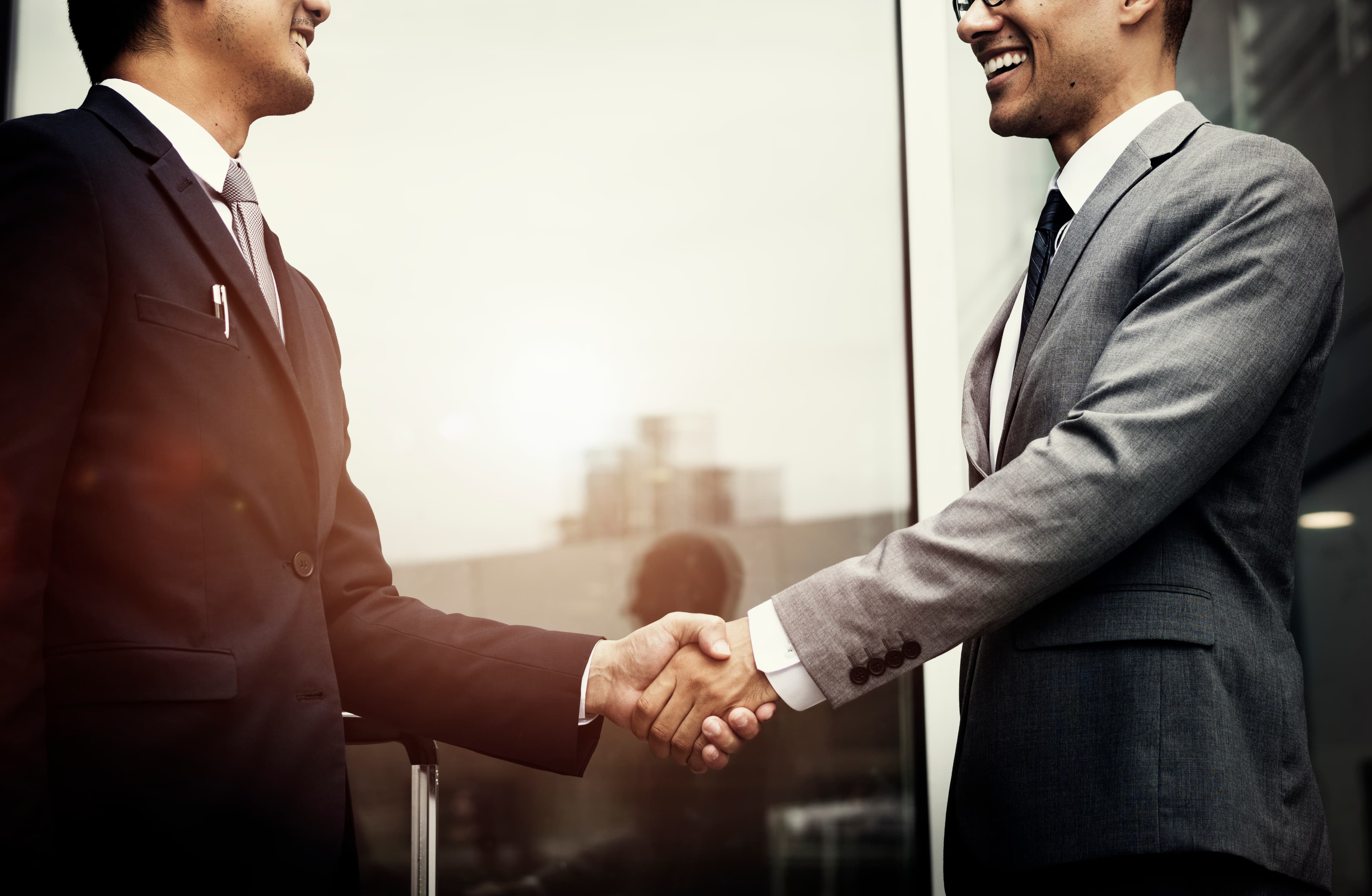 Professional business partnership - Two executives shaking hands in modern office setting